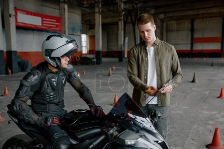 Photo for First lesson at motorcycle school. Instructor describing technical characteristics of motorcycle and safety traffic rules to student - Royalty Free Image