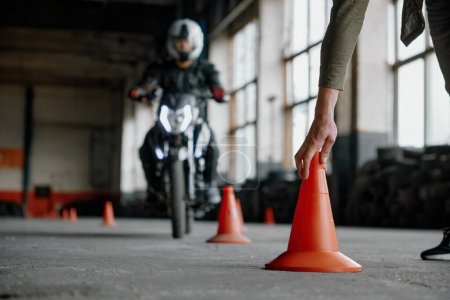 Photo for Motorbike driving school lesson with instructor putting cone on track front of student. Indoor moto drome training center - Royalty Free Image