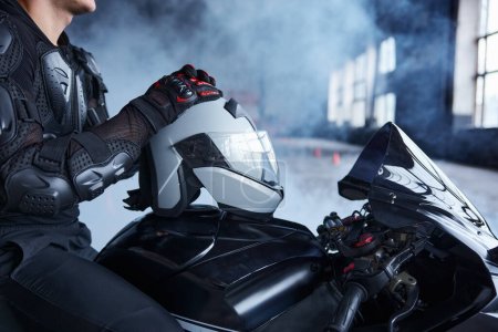 Téléchargez les photos : Gros plan motocycliste sur moto assis tenant casque de protection. Cours de formation à l'école de conduite professionnelle - en image libre de droit