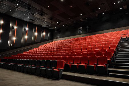 Téléchargez les photos : Intérieur vide de la salle de cinéma avec rangée de sièges rouges attendant le public des visiteurs. Lieu pour regarder un film et un événement de première - en image libre de droit