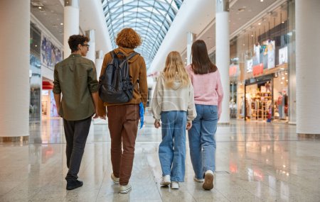 Photo for Group of young friends shopping at big city store center back view. Teenagers classmates walking for fun and joyful entertainment with black friday sale discount - Royalty Free Image