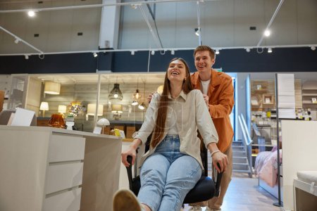 Photo for Overjoyed young family couple fooling around at furniture store. Happy man and woman lovers enjoying shopping process - Royalty Free Image