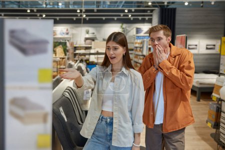 Photo for Excited young couple rejoicing seeing great price clearance and discounts at modern furniture shop store department. Shopping with sale, Black Friday or Christmas wholesale concept - Royalty Free Image