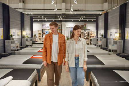 Photo for Young man and woman couple looking for new comfortable bed at modern furniture shop. Family shopping time concept - Royalty Free Image