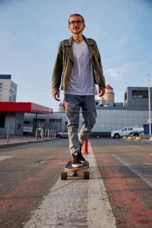 Photo for Hipster guy riding skateboard prefers eco-friendly transportation among city. Cool man moving by longboard doing for shopping at supermarket - Royalty Free Image