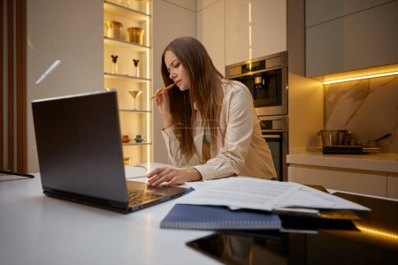 Téléchargez les photos : Femme utilisant un ordinateur portable faire de la recherche de travail ou d'étudier en ligne à partir de la maison. Concentré attrayant femmes freelance cours web d'apprentissage ou d'avoir appel virtuel réunion d'affaires - en image libre de droit