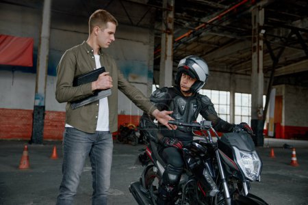 Photo for Personal lesson at motorcycle school. Male instructor teaching young biker explaining important things before start to move - Royalty Free Image