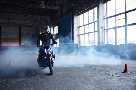 Foto de Motorista haciendo truco difícil y peligroso en su moto a caballo rápido en el aeródromo de la escuela de conducción - Imagen libre de derechos