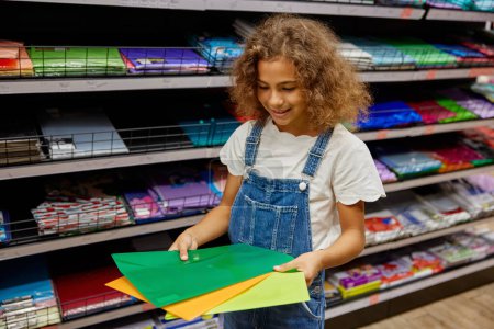Photo for Little school girl choosing plastic folder for notebooks at stationery store. Cute female child buying daily necessities for study - Royalty Free Image