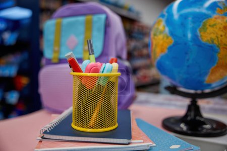 Foto de Caja con papelería, bolso escolar y globo de tierra que se muestra en la mesa en la tienda preparada para la venta. Descuento estudiar artículo para la compra enfoque selectivo - Imagen libre de derechos