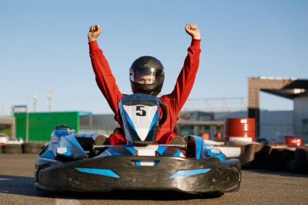 Photo for Happy go-cart driver raising hands up rejoicing and celebrating win. Carting extreme sports competition and victory in championship - Royalty Free Image