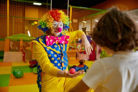 Photo for Playful funny clown showing tricks with nose carnival decoration at birthday party. Curious boy watching animator with interest. Birthday party enjoyment concept - Royalty Free Image
