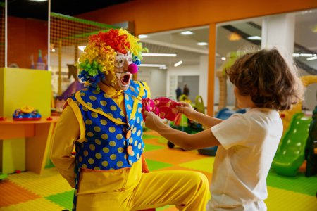 Foto de Animador payaso divertido y niño jugando en la sala de juegos cubierta del moderno centro de entretenimiento para niños - Imagen libre de derechos
