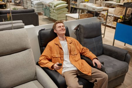Photo for Relaxed man sitting at comfortable leather armchair feeling peace and no stress enjoying shopping time at modern furniture retail market - Royalty Free Image