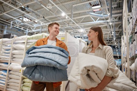 Photo for Happy young couple choosing new bedding blanket for home at linen store. Man and woman feeling satisfaction of shopping with sales buying two item for price of one - Royalty Free Image