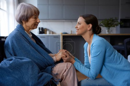 Photo for Side view portrait of middle age daughter holding hands looking into eyes of elderly mother sharing love, support and care. Old parents and children connection and loving relationship concept - Royalty Free Image