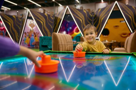 Photo for Active little boy child playing air hockey at entertainment center. Portrait of healthy happy kid enjoying carefree childhood time - Royalty Free Image