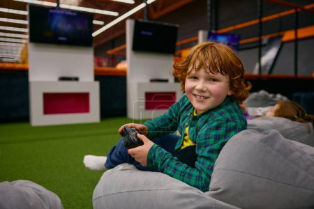 Portrait d'enfant garçon souriant heureux avec des joues roses jouant au jeu vidéo dans le centre des enfants. Temps de jeu