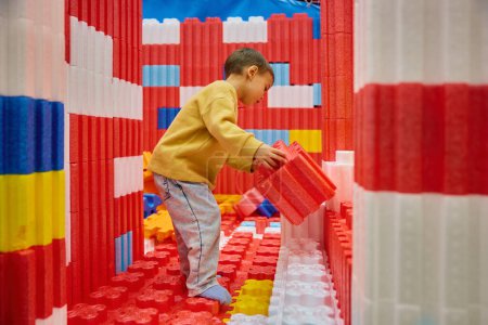Photo for Little boy child playing with huge building blocks in entertainment center. Safety soft colorful construction site for kids at day care playground - Royalty Free Image