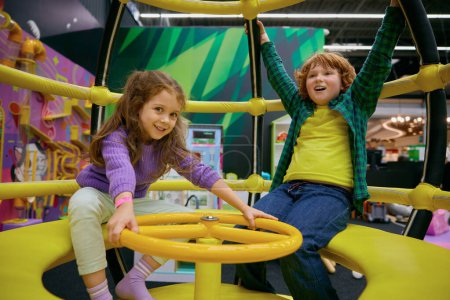 Foto de Feliz niños emocionados jugando en el carrusel interior en el centro de juegos. Actividad de fin de semana disfrute y diversión infancia - Imagen libre de derechos