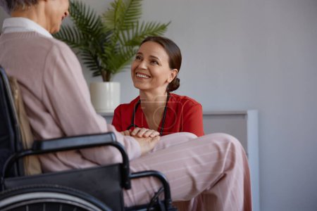 Téléchargez les photos : Infirmière médicale et patiente âgée assise en fauteuil roulant dans une maison de soins infirmiers pour la réadaptation. Travailleur social soutenant donner de l'espoir en consultation et prendre soin de la vieille dame à la retraite - en image libre de droit