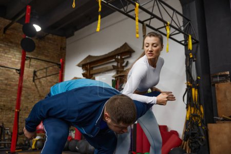 Woman training with man practicing martial arts at gym. Sport, health and strength development concept