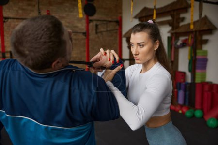 Foto de Mujer joven realizando movimiento de autodefensa de atacante con cuchillo. Entrenamiento de entrenamiento con instructor en el gimnasio - Imagen libre de derechos