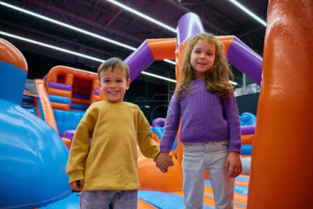 Téléchargez les photos : Portrait des enfants heureux excités divers appréciant des jeux dans la maison gonflable de rebond - en image libre de droit