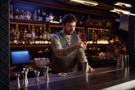 Téléchargez les photos : Bar professionnel mélangeant des ingrédients rafraîchissants ou des cocktails alcoolisés debout au comptoir de la boîte de nuit - en image libre de droit