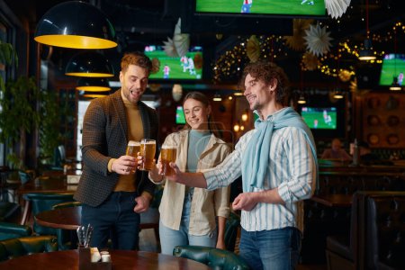 Felices amigos satisfechos tintineando vasos de cerveza celebrando la victoria del equipo de fútbol favorito en el partido pasando el fin de semana en el pub