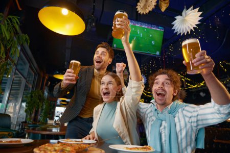 Overjoyed friends crazy screaming shouting supporting favorite soccer team during championship match watching at sports bar