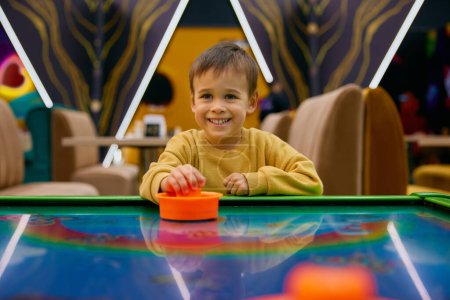 Photo for Active little boy child playing air hockey at entertainment center. Portrait of healthy happy kid enjoying carefree childhood time - Royalty Free Image