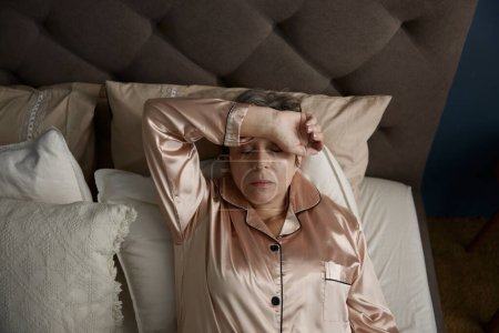 Photo for Sleepless upset lonely old woman suffering from insomnia, nightmares or depression lying in bed under blanket - Royalty Free Image