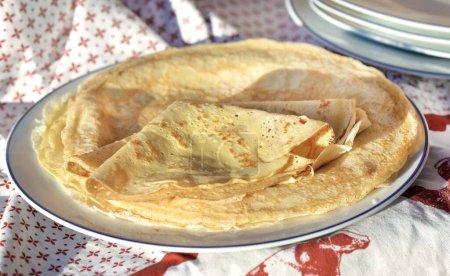 Téléchargez les photos : Crêpe traditionnelle française maison - crêpe pliée dans une assiette sur une nappe rouge et blanche - en image libre de droit