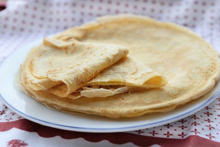Téléchargez les photos : Crêpe traditionnelle française pliée dans une assiette sur une nappe rouge et blanche - en image libre de droit