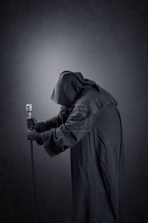 Foto de Asistente con capa encapuchada y bastón mágico sobre fondo oscuro brumoso - Imagen libre de derechos