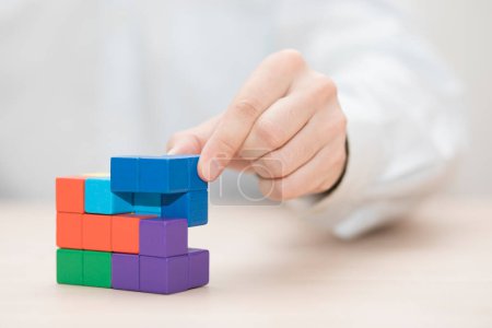 Photo for Man's hand stacking colorful wooden blocks. Business development concept - Royalty Free Image