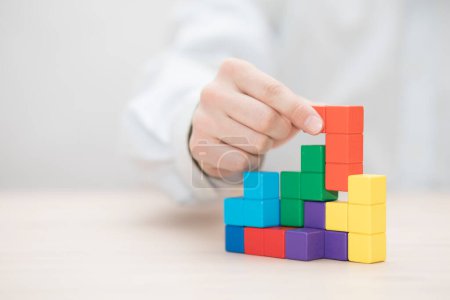 Photo for Man's hand stacking colorful wooden blocks. Business development concept - Royalty Free Image