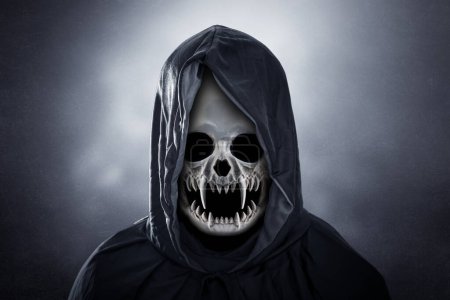 Photo for Grim reaper in hooded cloak over dark misty background at night - Royalty Free Image