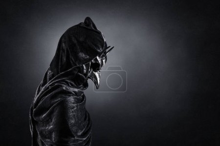 Photo for Creepy figure with animal horned skull over dark misty background - Royalty Free Image
