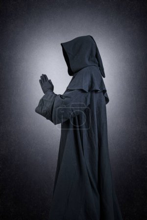 Photo for Medieval monk in hooded cloak praying in the dark - Royalty Free Image