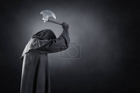 Photo for Man in black hooded cloak with axe over dark misty background - Royalty Free Image