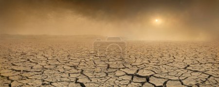Foto de Amplio panorama de tierra estéril agrietada con sol apenas visible a través de la tormenta de polvo, sequía y el concepto de desertificación - Imagen libre de derechos