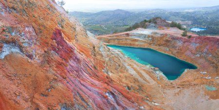 Foto de Minas de cobre abandonadas de Chipre. Gossan colorido (tapa de hierro) de la mina Alesto con pozo abierto lleno de agua, y el lago de la mina Memi a la distancia - Imagen libre de derechos