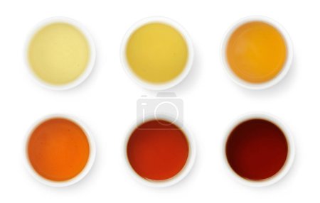 Foto de Brewed Chinese teas of different color in white bowls top view isolated on white - Imagen libre de derechos