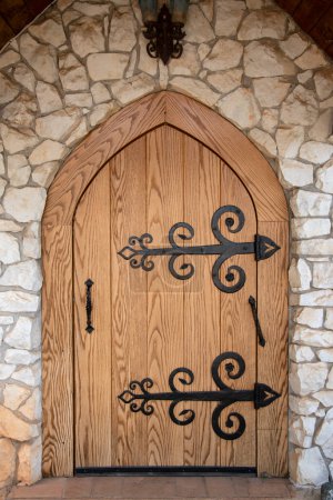 Foto de Puerta de madera arqueada adornada con bisagras grandes negras. - Imagen libre de derechos