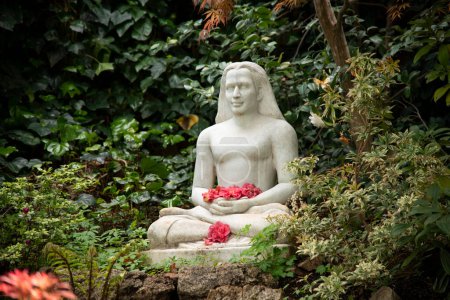 Foto de Jardín de meditación con escultura sentada sosteniendo flores - Imagen libre de derechos