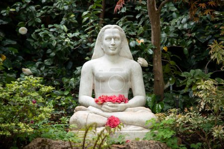 Téléchargez les photos : Jardin de méditation avec sculpture assise tenant des fleurs - en image libre de droit