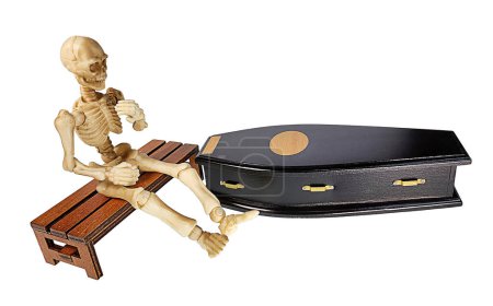 Skeleton sitting next to a Black Wooden Coffin Used to Bury People Who Have Passed