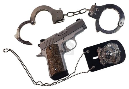 Foto de Pistola de metal plateado de 9mm con esposas y placa de policía - Imagen libre de derechos